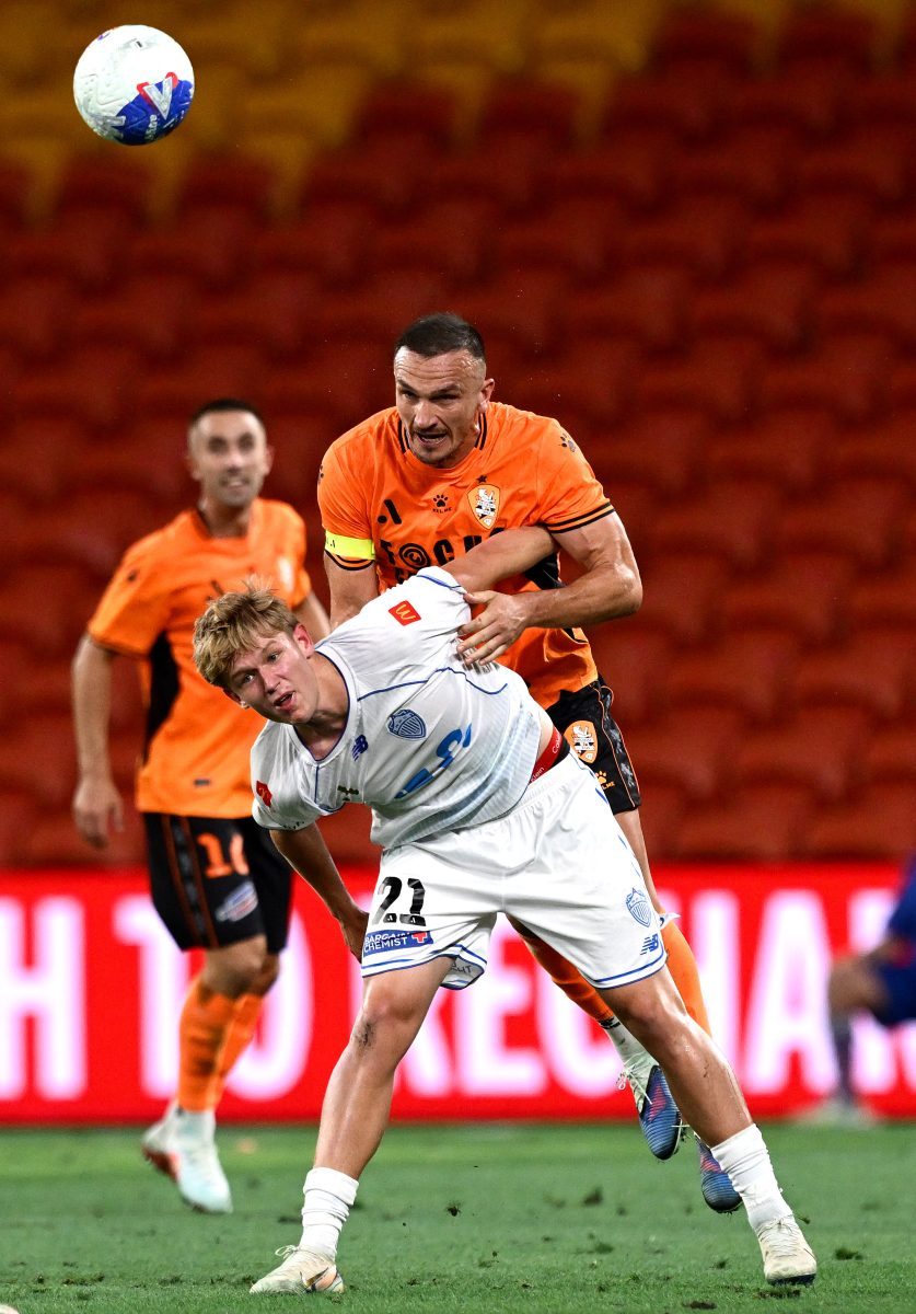 Tom Aldred of the Roar and Isa Prins of Auckland FC compete for the ball at Suncorp Stadium.